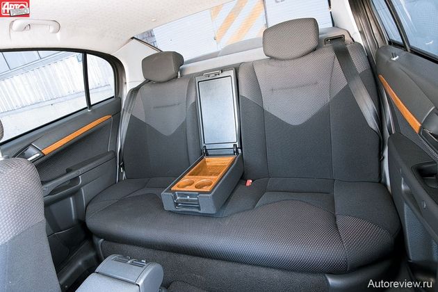 Сзади потолок пониже, но до тесноты далеко, есть удобный подлокотник, а места для ступней пассажиров — масса
